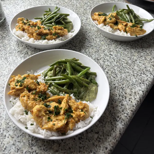 Trois assiettes de riz, d'émincé de poulet en sauce et de haricots verts