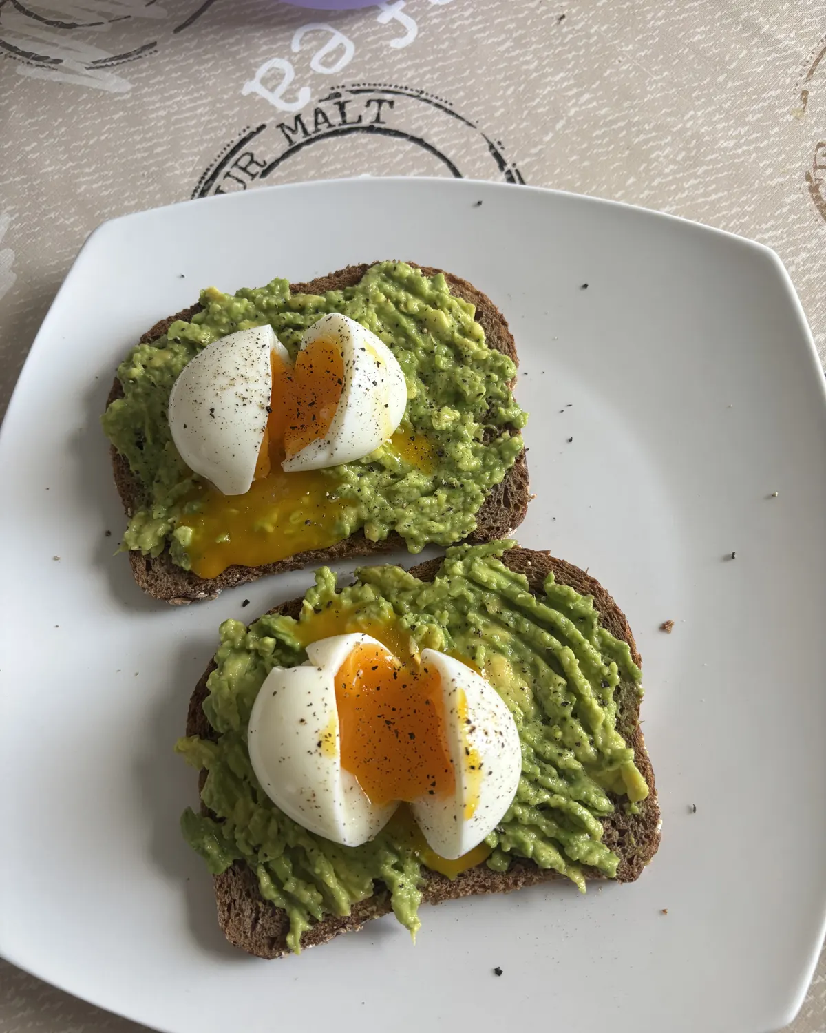 Tartines de pain complet garnies d'avocat écrasé et d'œufs mollets coupés en deux