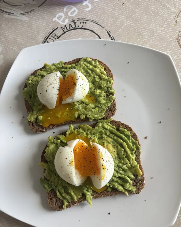 Tartines de pain complet garnies d'avocat écrasé et d'œufs mollets coupés en deux